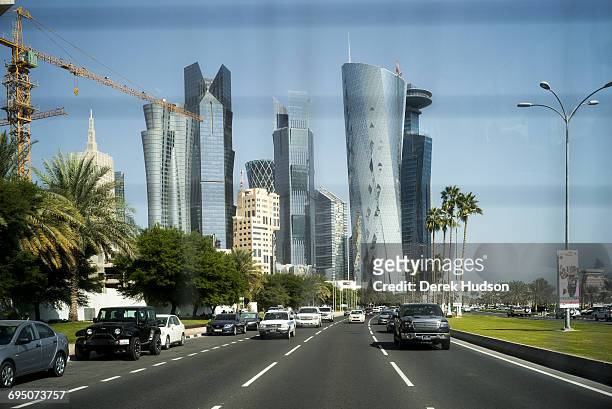 View of skyscraper buildings of the city of Doha as seen from the from the back of a bus driving on the Corniche road.