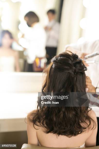 a woman making up by a make-up artist in front of a mirror - backstage hairdresser stock-fotos und bilder