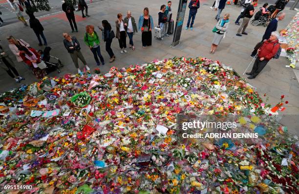Pedestrians stop to look at floral tributes left by well-wishers on London Bridge in London on June 12 following the June 3 terror attack that...