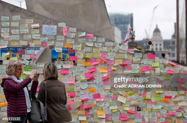 Pedestrians stop to look at messages left by well-wishers on London Bridge in London on June 12 following the June 3 terror attack that targeted...