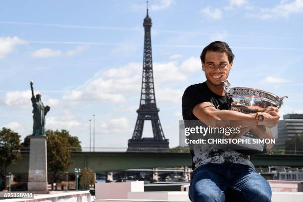 Spain's Rafael Nadal poses with the winner's trophy a day after he won the men's Roland Garros 2017 French Open on June 12, 2017 in Paris, with the...