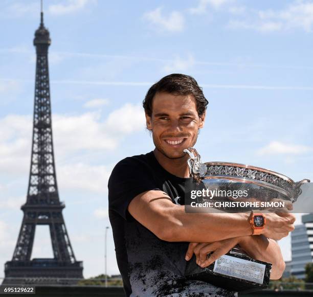 Spain's Rafael Nadal poses with the winner's trophy a day after he won the men's Roland Garros 2017 French Open on June 12, 2017 in Paris, with the...