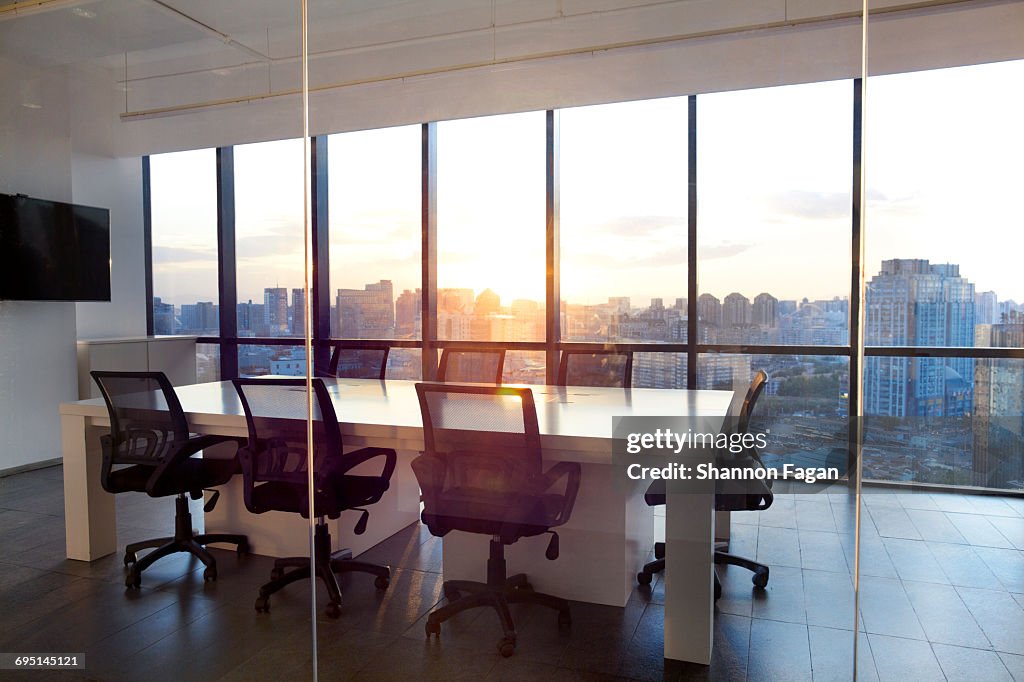 Meeting room with glass wall cityscape and sunset