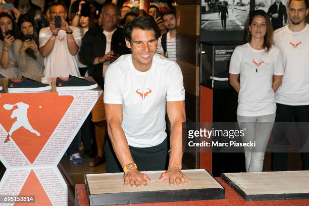 Rafael Nadal casts a print of his hands in clay during a promotional event at the 'Nike Store' on the Champs-Elysees avenue, one day after winning...