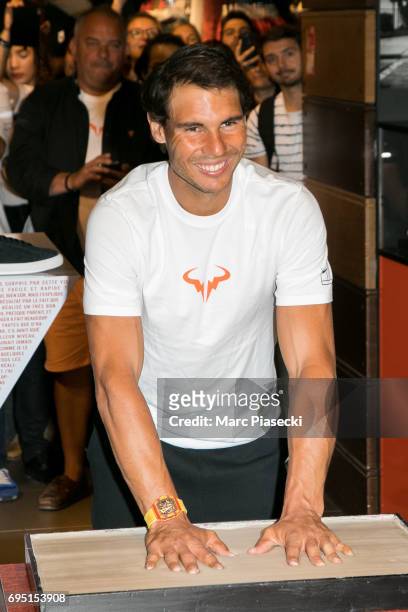 Rafael Nadal casts a print of his hands in clay during a promotional event at the 'Nike Store' on the Champs-Elysees avenue, one day after winning...
