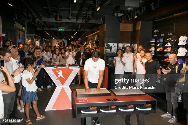 Rafael Nadal casts a print of his hands in clay during a promotional event at the 'Nike Store' on the Champs-Elysees avenue, one day after winning...