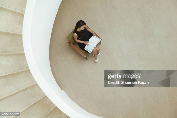 woman sitting in chair with book in building lobby - beige dress stock pictures, royalty-free photos & images