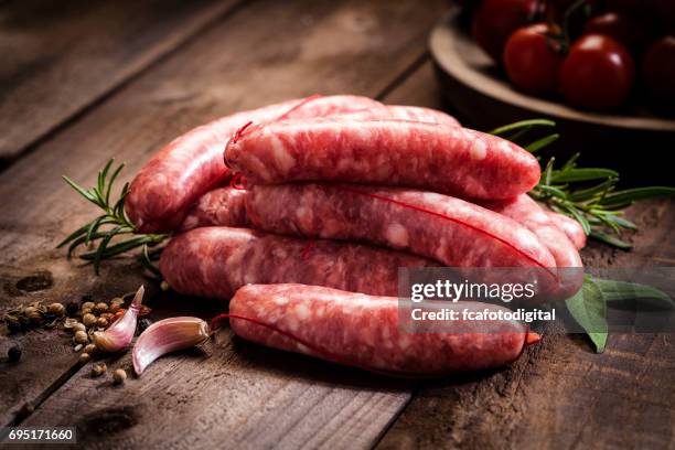 sausages heap on dark wood table - raw sausages stock pictures, royalty-free photos & images