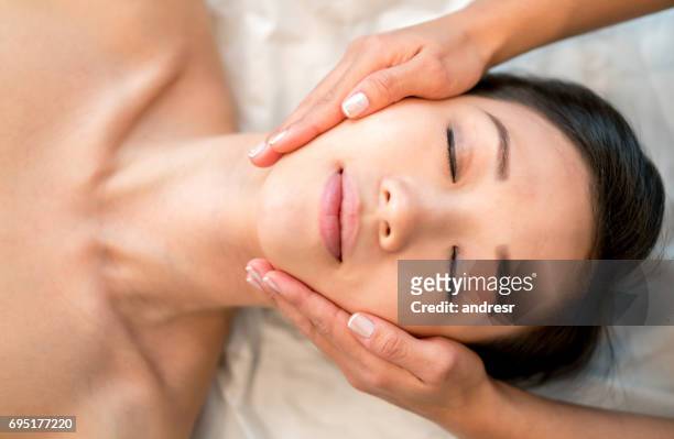 mujer asiática recibiendo un masaje facial en el spa - máscara facial fotografías e imágenes de stock