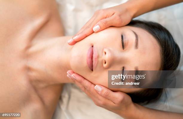 asian woman getting a face massage at the spa - asian beauty face stock pictures, royalty-free photos & images