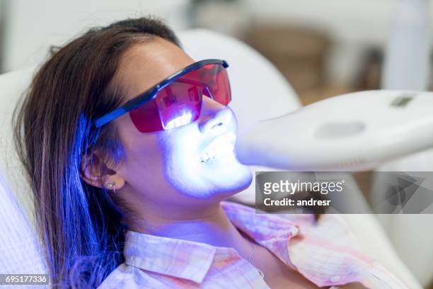 donna che sbianca i denti laser - denti foto e immagini stock