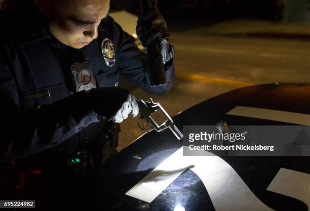Police officer from the 77th Division gang unit examines a .38 caliber pistol recovered from a roof after it was thrown by a gang member May 21, 2017...