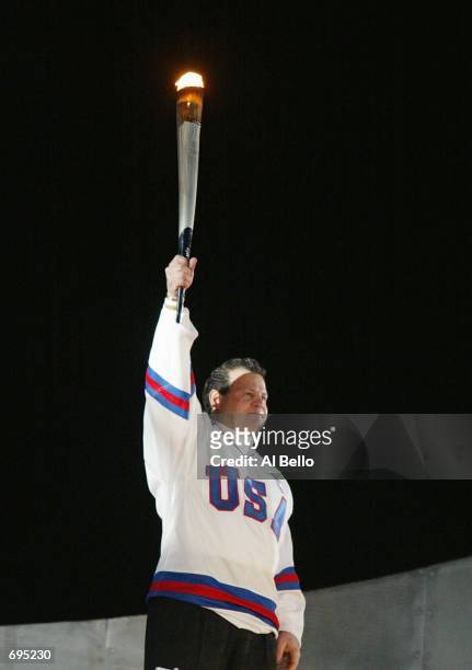 : Michael Eruzione of the 1980 US hockey team holds the Olympic Torch before lighting the Olympic flame at the Opening Ceremony of the 2002 Salt Lake...