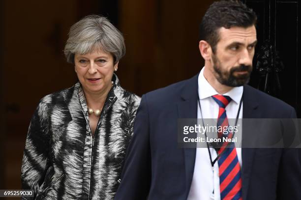 Security guard walks wth British Prime Minister Theresa May as she leaves 10 Downing Street for the 1922 committee on June 12, 2017 in London,...