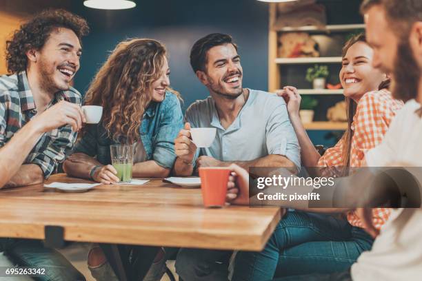 group of young people sitting and talking in cafe - coffee meeting with friends stock pictures, royalty-free photos & images