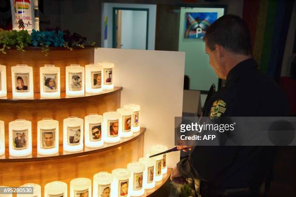 An Orlando Police officer lights candles, adorned with the likenesses of of the Pulse nightclub vicitms one year after the mass shooting in Orlando,...