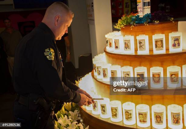 An Orlando Police officer lights candles, adorned with the likenesses of of the Pulse nightclub vicitms one year after the mass shooting in Orlando,...