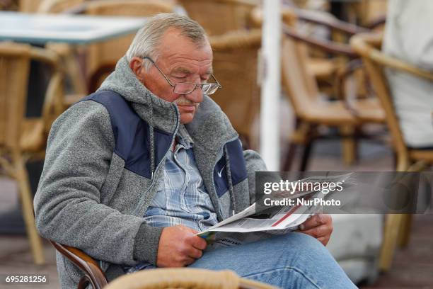 Man is seen reading a newspaper on the terras of an outdoor pub in the old market square in Bydgoszcz, Poland on 10 June, 2017.