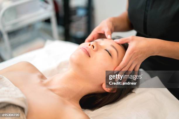 hermosa mujer asiática recibiendo un masaje facial en el spa - máscara facial fotografías e imágenes de stock