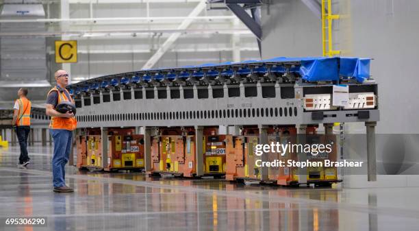 Worker operates an automated guided vehicle carrying a wing part through the Boeing 777X Composite Wing Center on June 12, 2017 in Everett,...
