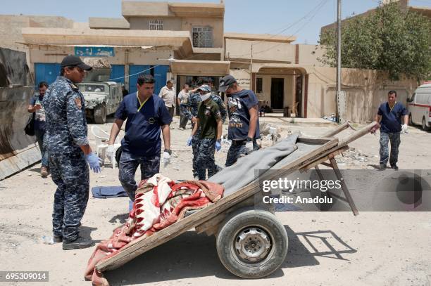 Iraqi army members prepare to place a dead body, covered with a blanked left on back of a tumbre, inside of a body bag in Mosul, Iraq on June 12,...