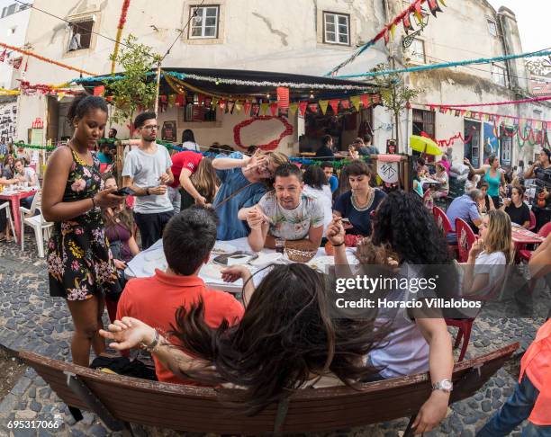 Visitors dine on sardines in one of many food stalls offering sardines, a must for visitors, in the old quarter of Mouraria on June 12, 2017 in...