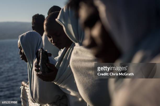 Refugees and migrants look out at Italy as they arrive in port on the Migrant Offshore Aid Station Phoenix vessel on June 12, 2017 in Reggio...