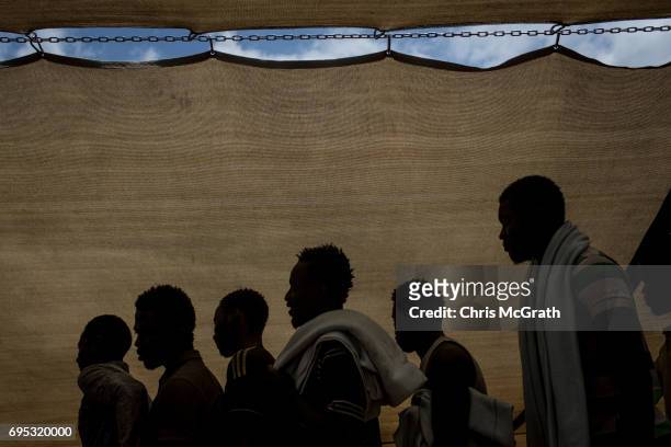 Refugees and migrants are seen waiting to disembark the Migrant Offshore Aid Station Phoenix vessel after arriving in port on June 12, 2017 in Reggio...