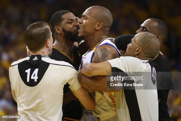 David West of the Golden State Warriors and Tristan Thompson of the Cleveland Cavaliers are separated by referee Ed Malloy and referee Dan Crawford...