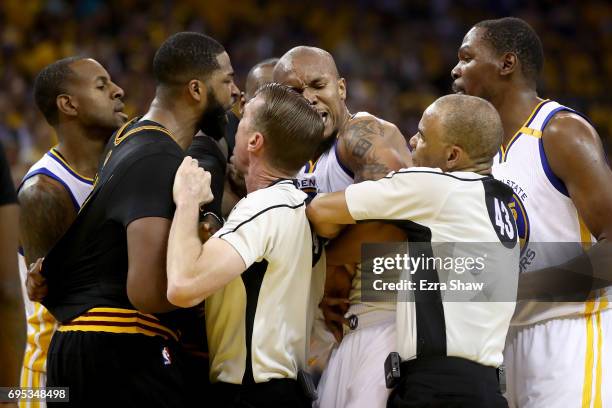 David West of the Golden State Warriors and Tristan Thompson of the Cleveland Cavaliers are separated by referee Ed Malloy and referee Dan Crawford...