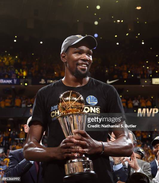 Kevin Durant of the Golden State Warriors holds up the Bill Russell Finals MVP Trophy after winning the Finals MVP after Game Five of the 2017 NBA...
