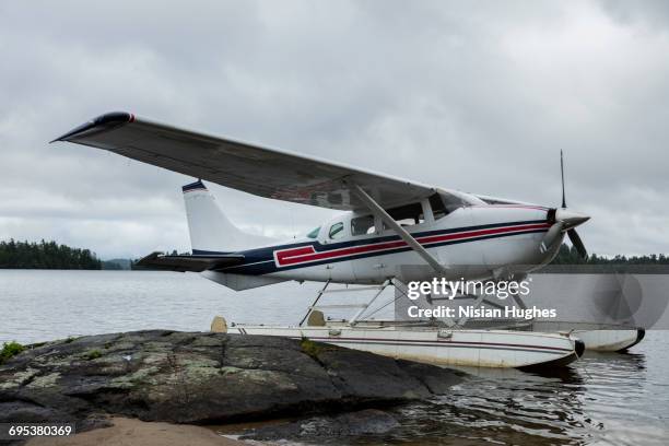 seaplane docked along rocks on lake - see saranac lake stock-fotos und bilder