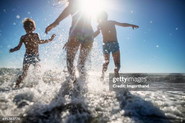 chlidren running happily in the sea - drenched stock pictures, royalty-free photos & images