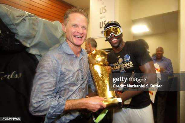 Steve Kerr and Draymond Green of the Golden State Warriors celebrate with the Larry O'Brien Trophy in the locker room after winning the NBA...