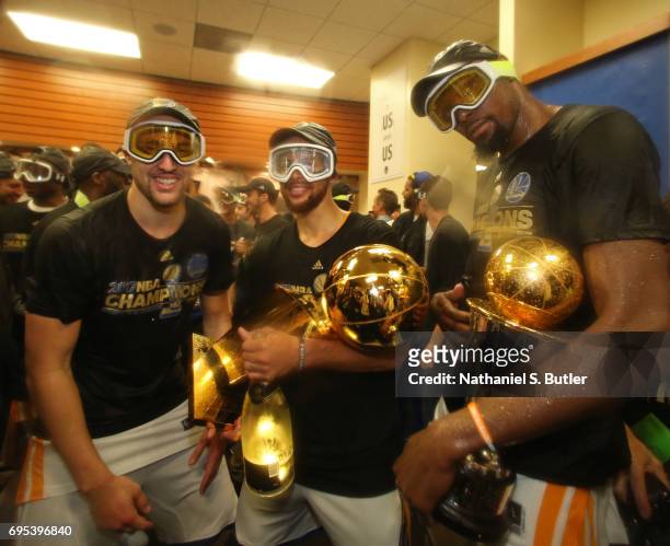 Stephen Curry, Klay Thompson and Kevin Durant of the Golden State Warriors celebrate with the Larry O'Brien Trophy and the Bill Russell Finals MVP...