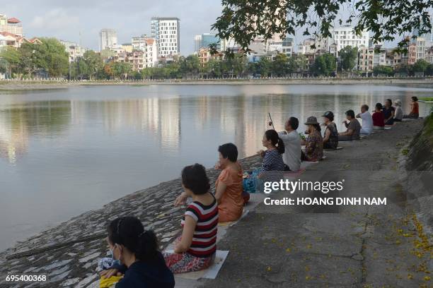 This picture taken on June 10, 2017 shows residents practicing Falun Gong meditation exercises next to a lake in downtown Hanoi. / AFP PHOTO / HOANG...