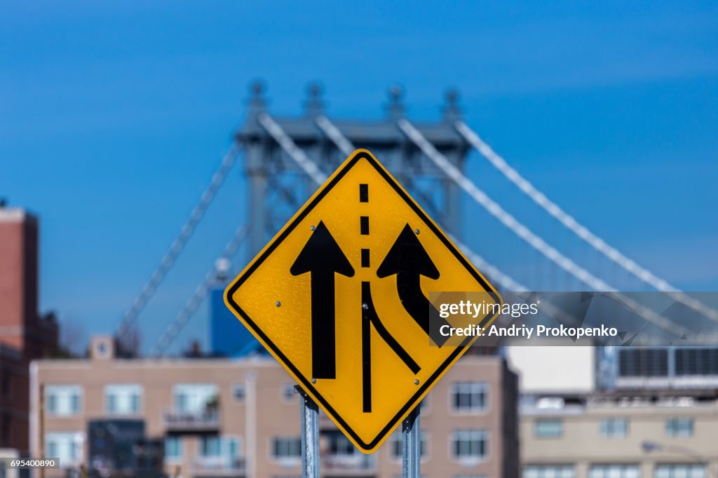 Yellow road sign with Manhattan Bridge in the background
