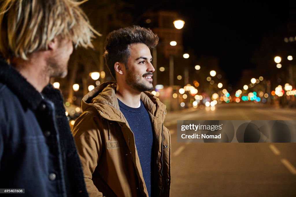 Friends talking while walking in city at night