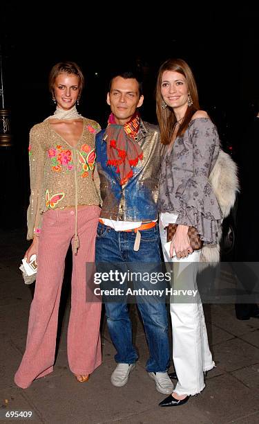 Fashion designer Matthew Williamson poses for photographers with two models as he arrives at the opening of the Mario Testino photography exhibition...