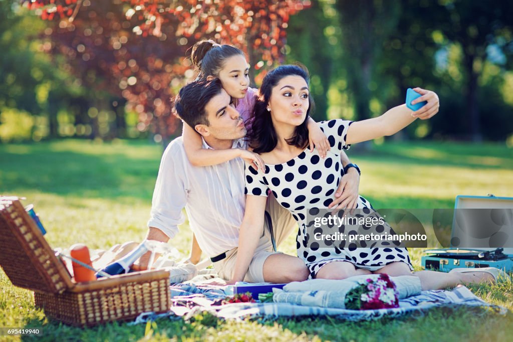 Gelukkige familie maakt grappige eend gezicht en nemen selfie op de picknick in het park