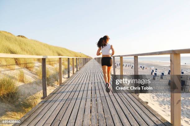 woman running on a board walk along the beach into the horizon - sylt stock-fotos und bilder
