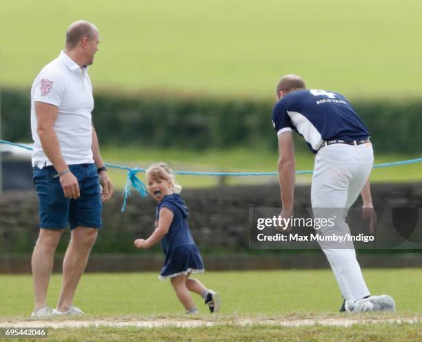 Mike Tindall looks on as daughter Mia Tindall is chased by Prince William, Duke of Cambridge as they attend the Maserati Royal Charity Polo Trophy...