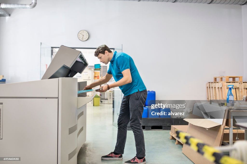 Male professional working on printing machine in industry