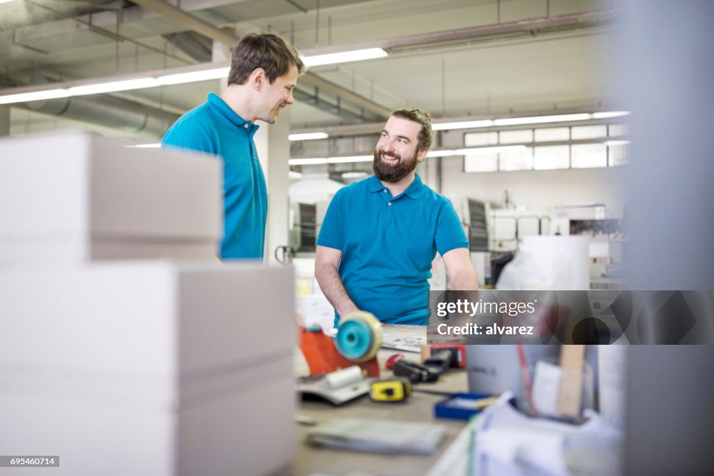 Zwei Menschen stehen und diskutieren in der Druckerei