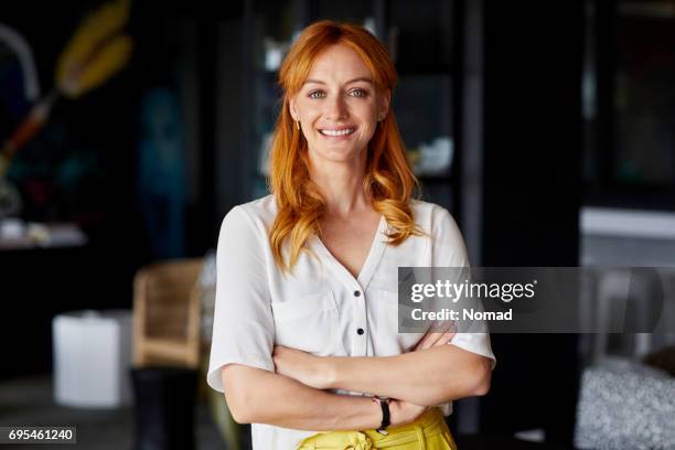 confident professional with arms crossed in office - redhead stock pictures, royalty-free photos & images