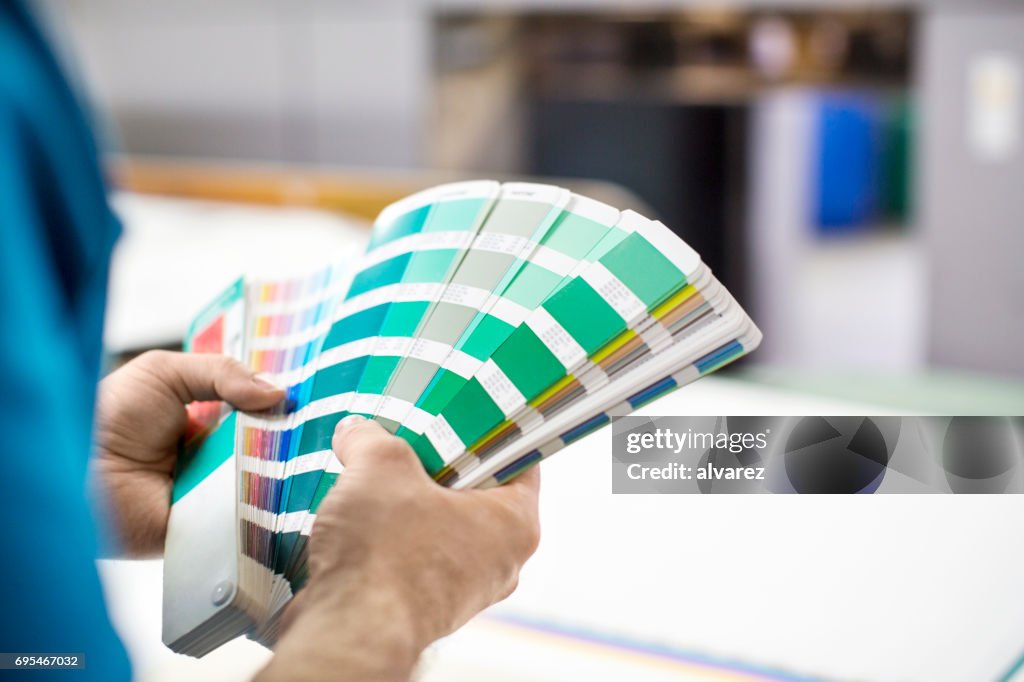 Mannhände mit Farbmuster an Druckmaschine