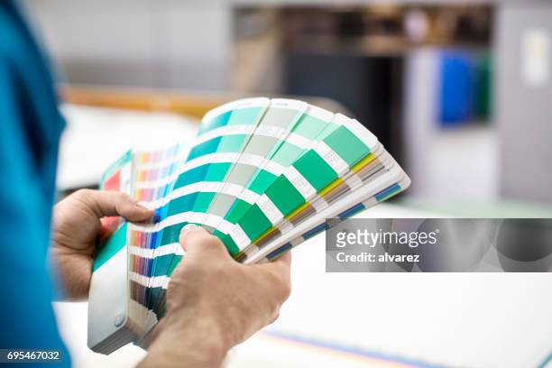mannhände mit farbmuster an druckmaschine - farbpalette stock-fotos und bilder
