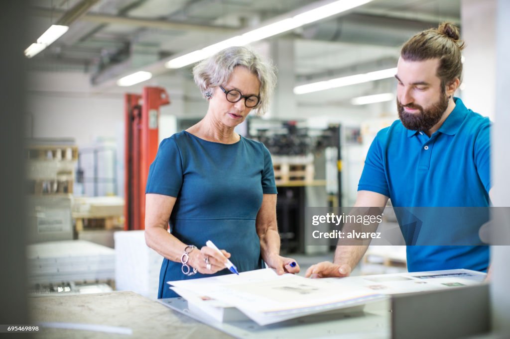Workers examining printouts at printing plant
