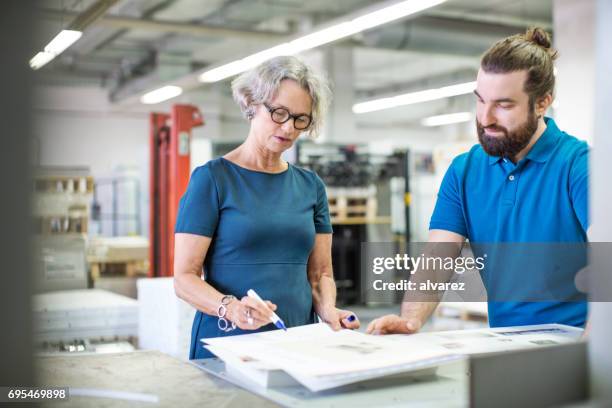 workers examining printouts at printing plant - printing press stock pictures, royalty-free photos & images