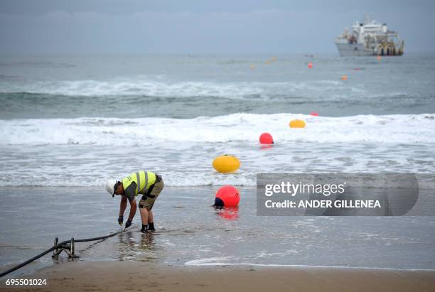 An operator works during the mooring of an undersea fiber optic cable at Arrietara beach near the Spanish Basque village of Sopelana on June 13,...